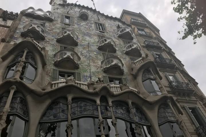 La fachada de la Casa Batlló, con sus balcones en forma de máscara y el mosaico de colores, vista desde la calle