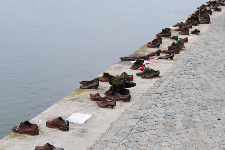 Hilera de zapatos de hierro en el borde del muelle del Danubio, con algunas flores