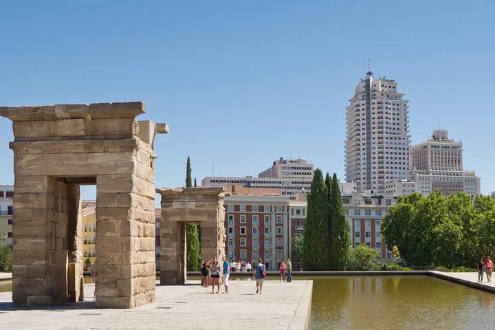 Pórticos de piedra del Templo de Debod junto a su estanque, con la Torre de Madrid al fondo