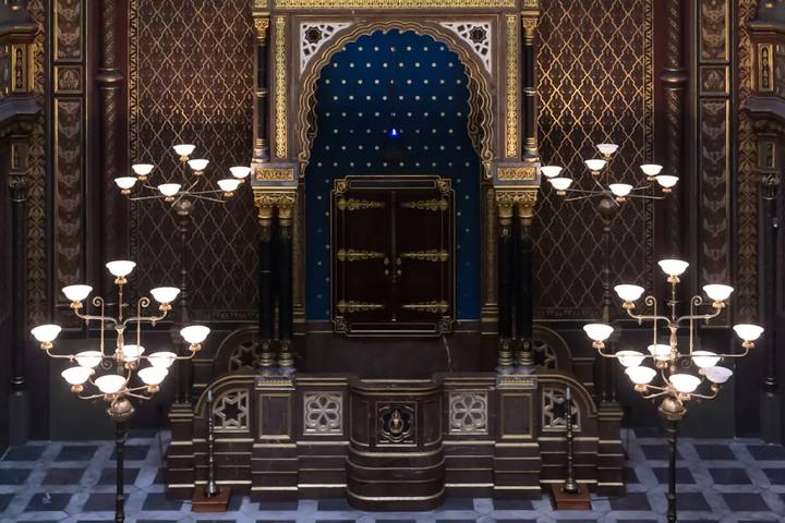 El interior de la sinagoga Española, una de las del Museo Judío, con el arca de la Torá bajo un arco morisco azul y lámparas doradas