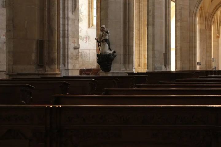 El interior gótico de la catedral de Santa Bárbara de Kutná Hora, con bancos de madera, columnas y la estatua de un minero