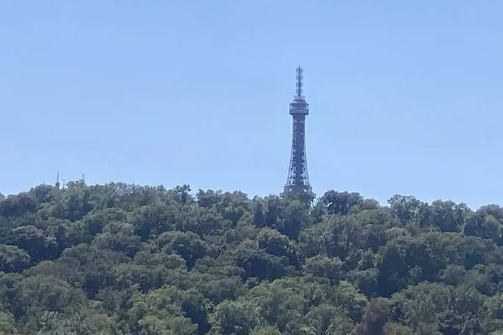 La torre metálica de Petřín asomando sobre el bosque de la colina, con el cielo azul