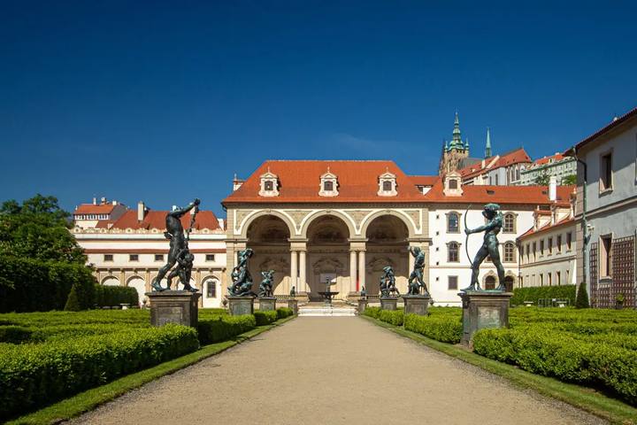 El paseo de grava entre setos de los jardines de Wallenstein, con estatuas de bronce y la logia de tres arcos al fondo