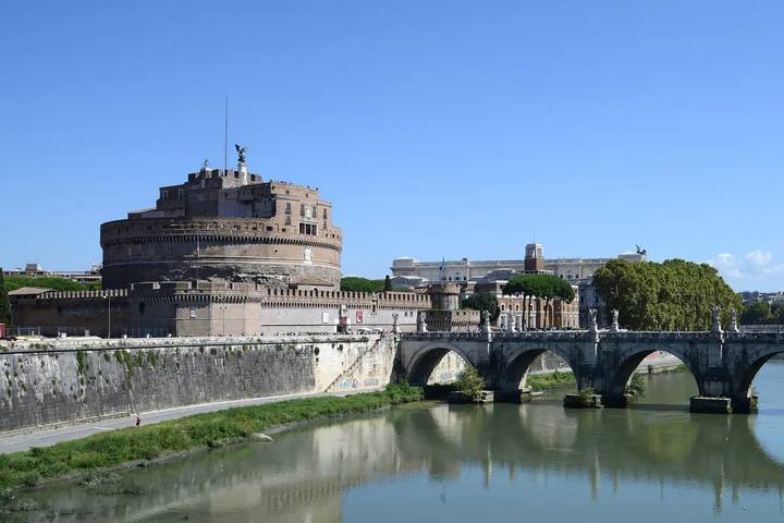 Castel Sant'Angelo junto al río Tíber y el puente de Sant'Angelo con sus estatuas, en un día soleado de cielo azul