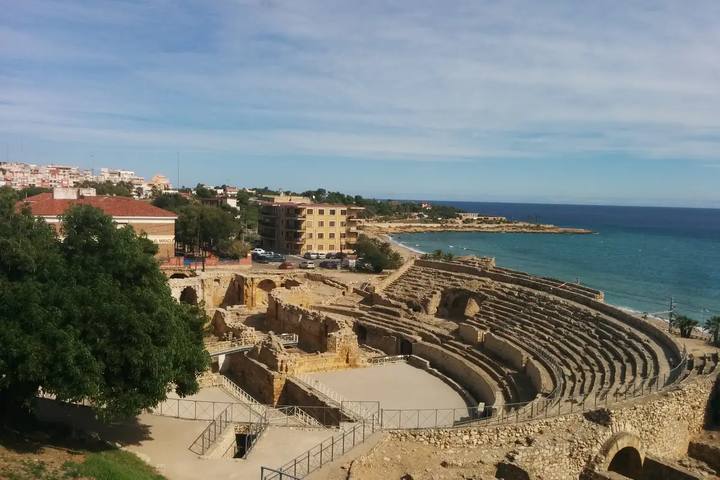 Gradas y arena del anfiteatro romano de Tarragona junto a la playa del Miracle y el mar Mediterráneo azul