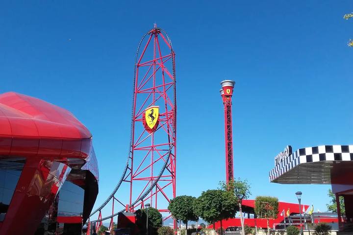 Torre roja de la montaña rusa Red Force y la torre de caída de Ferrari Land bajo un cielo azul despejado