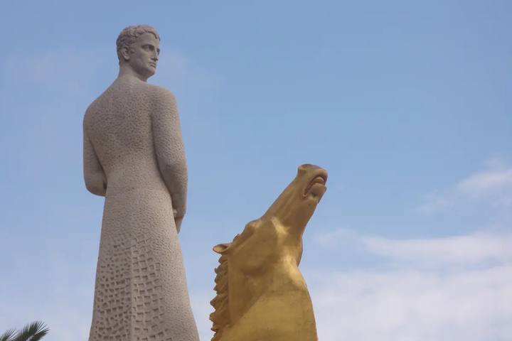 Estatua de piedra del rey Jaume I junto a la proa dorada con cabeza de caballo del monumento del paseo de Salou