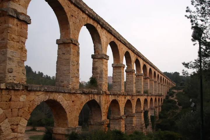 Doble arcada de piedra dorada del acueducto romano de Les Ferreres, el Pont del Diable, entre pinos cerca de Tarragona