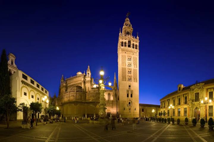 La Giralda y la Catedral de Sevilla iluminadas al anochecer desde la plaza Virgen de los Reyes