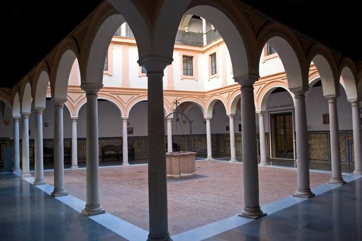 Claustro del Museo de Bellas Artes de Sevilla con arcos sobre columnas y un pozo en el centro