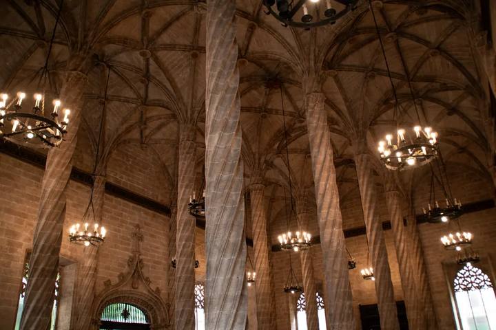 Columnas helicoidales y bóvedas góticas de la Sala de Contratación de la Lonja de la Seda de Valencia, con lámparas encendidas