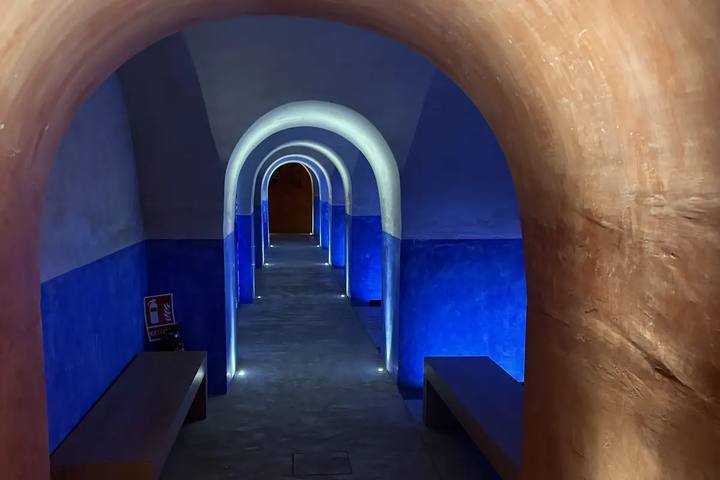 Galería abovedada del refugio antiaéreo del Ayuntamiento de Valencia, con arcos sucesivos iluminados en azul y bancos