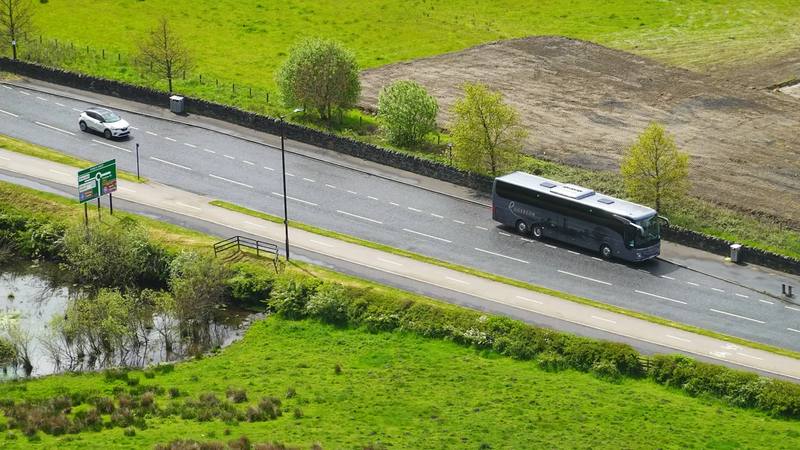 Autocar por una carretera entre campos verdes